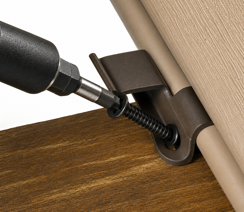 Close-up of a dark metal door hinge bracket being secured with a screwdriver, shown installed between a wood surface and a beige door panel.