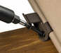 Close-up of a dark metal door hinge bracket being secured with a screwdriver, shown installed between a wood surface and a beige door panel.